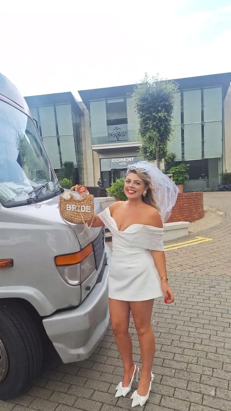 Bride-to-be in veil beside the party bus at the Stormont Hotel