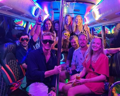 Mixed group celebrating on board the party bus under neon lighting