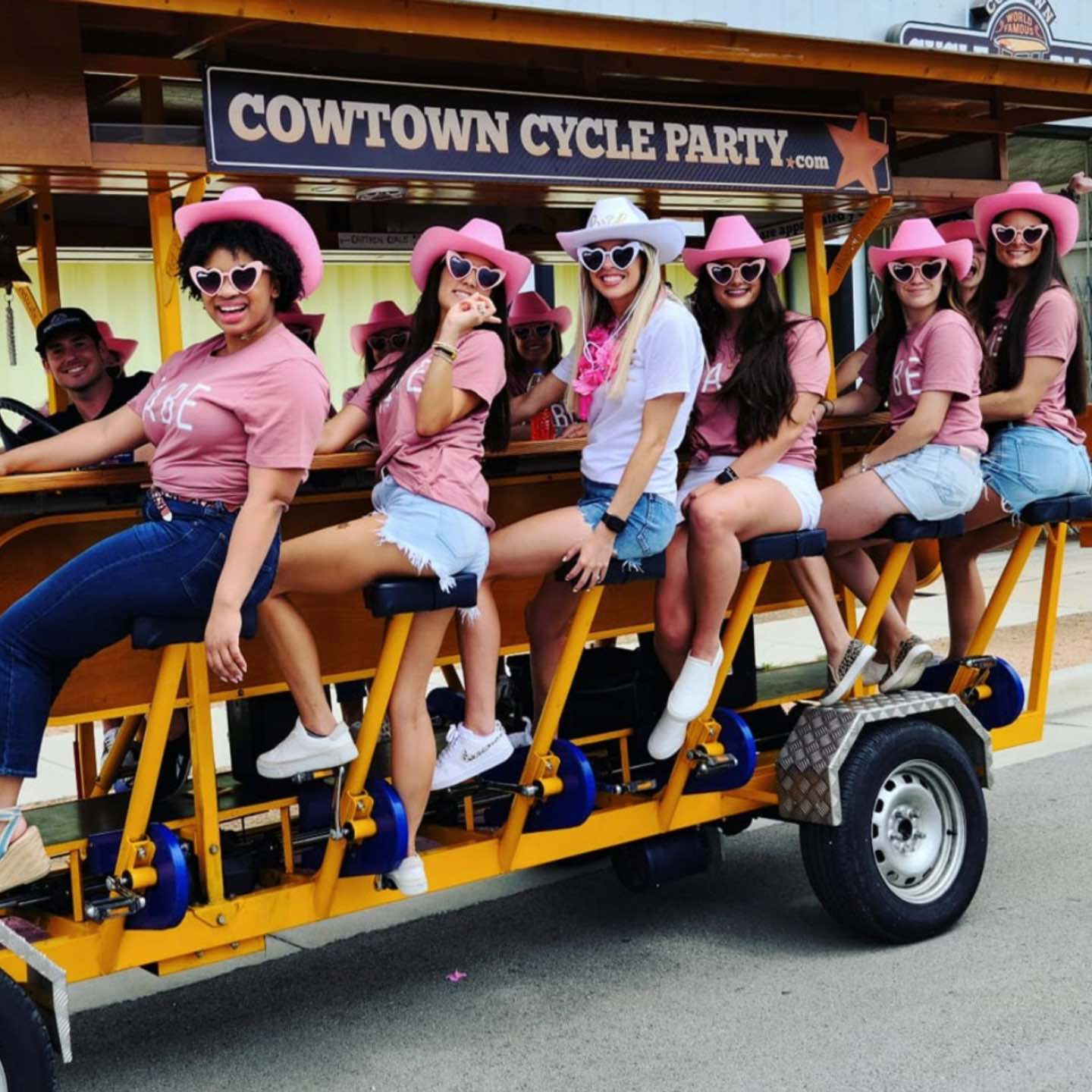 Hen party group pedalling a 15-person party bike on a daytime town-centre circuit