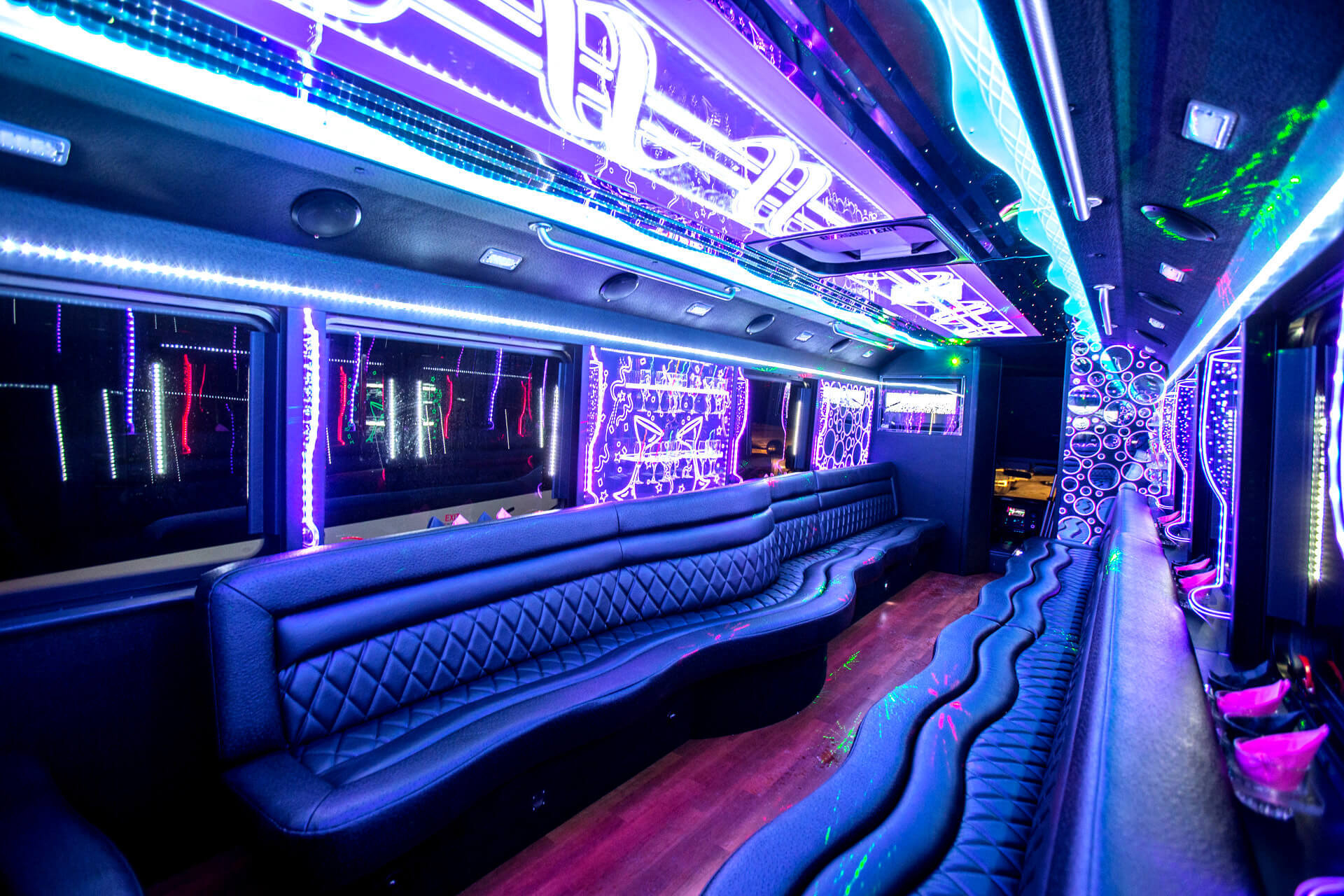 Party bus interior with leather booth seating and neon ceiling lighting