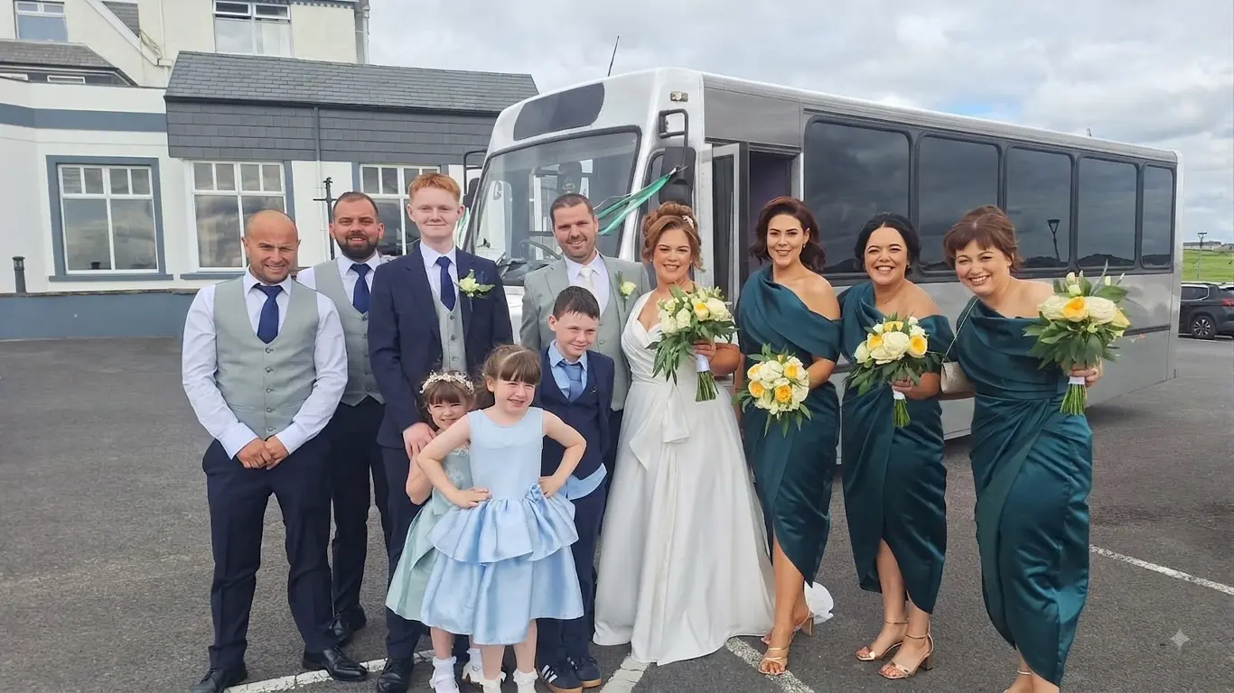 Wedding party and family photographed with the party bus outside the venue