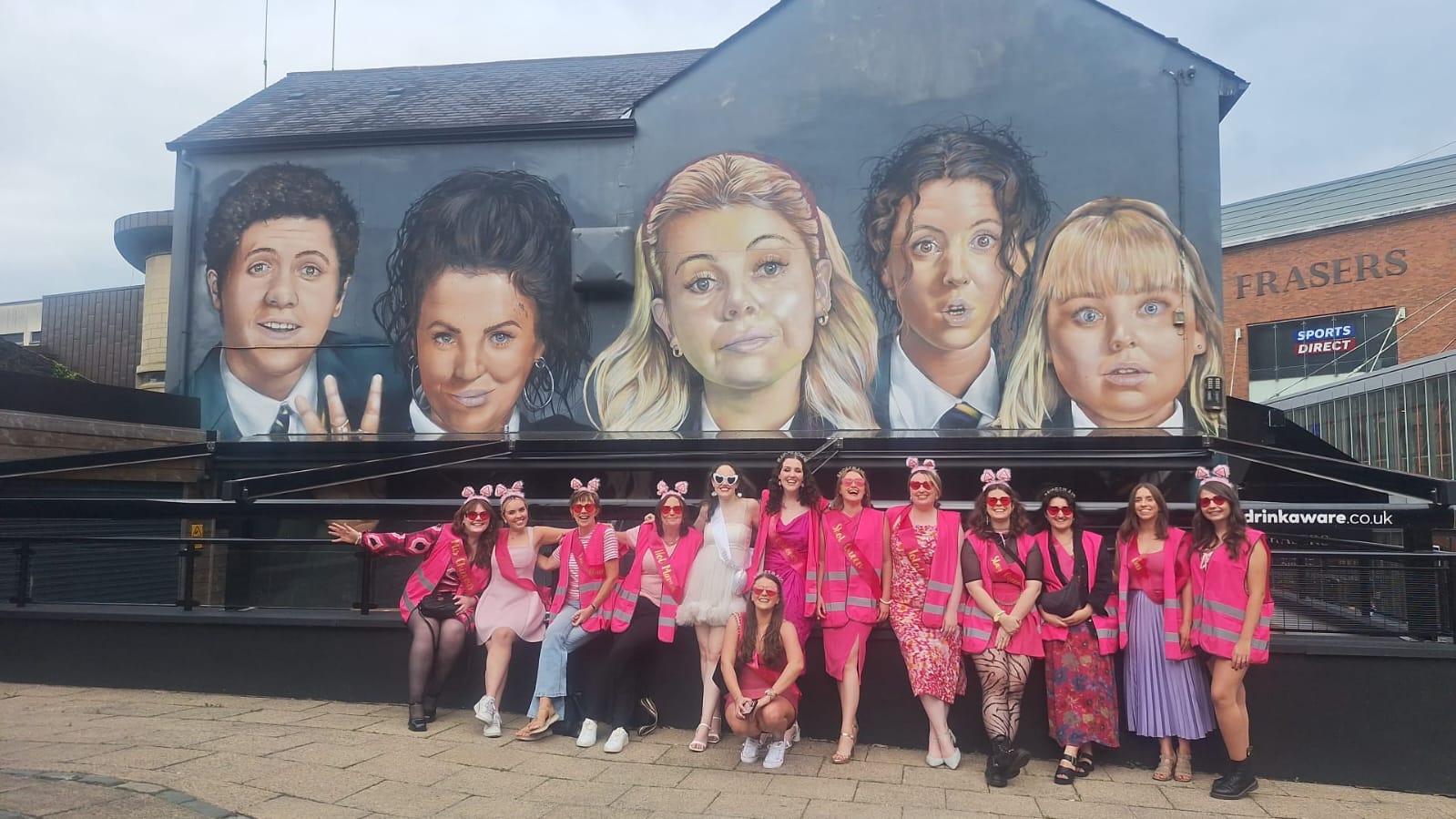 Hen party group at the Derry Girls mural during a party bus day out